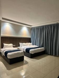 duas camas num quarto de hotel com cortinas em Aladnan hotel em Aqaba