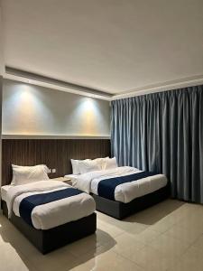 two beds in a hotel room with curtains at Aladnan hotel in Aqaba +26 photos