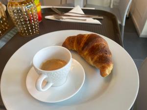 a plate with a cup of coffee and a croissant at Enjoy Garden - Flavio Baracchini 9 in Milan