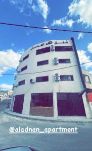 a tall white building with red windows on a street at Aladnan hotel in Aqaba