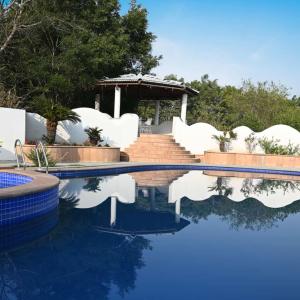 a swimming pool with white chairs and the reflection in the water at pool loft in Jaipur