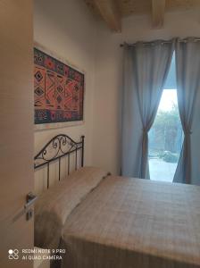 a bedroom with a bed and a window with curtains at VerdeMare in Rodi Garganico