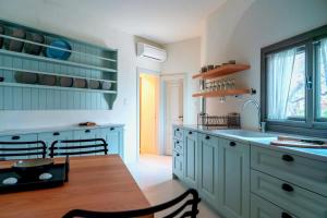 a kitchen with blue cabinets and a wooden table at Samos Serenity - Classic Retreat near the beach in Koumeika