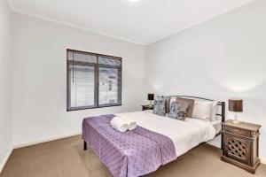 a white bedroom with a bed and a window at Bayside Bungalow in Glenelg