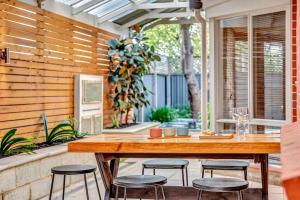 an outdoor patio with a wooden table and stools at Bayside Bungalow in Glenelg