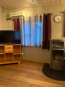 ein Wohnzimmer mit einem TV und einer Uhr an der Wand in der Unterkunft Apartment Roth in Roth