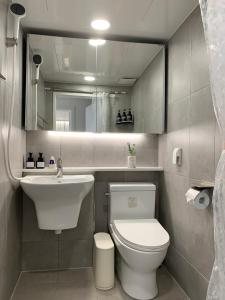 a bathroom with a toilet and a sink and a mirror at Comma 2, Cozy Semi-basement in Seoul