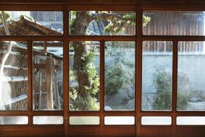 una ventana con vistas a un árbol en el exterior en DENIM HOUSE BON en Kurashiki
