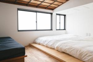 1 Schlafzimmer mit einem weißen Bett und 2 Fenstern in der Unterkunft DENIM HOUSE BON in Kurashiki