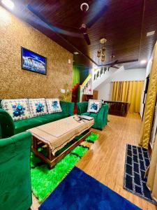un soggiorno con divani verdi e un tavolo di The Sunrise Villa Homestay a Rishikesh