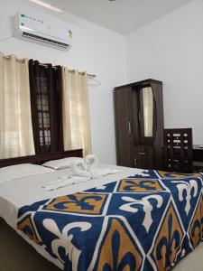 1 dormitorio con 1 cama con manta azul y blanca en Enna homestay, en Varkala