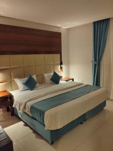 1 dormitorio con 1 cama grande con almohadas azules en شقق اطلالة أبحر للشقق المخدومة en Yeda