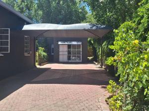 eine steinerne Einfahrt, die zu einem Haus mit einer Garage führt in der Unterkunft Wisteria Cottages in Bloemfontein