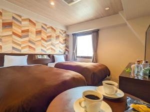 a hotel room with two beds and a table with cups of coffee at Hotel New Gaea Ube in Ube