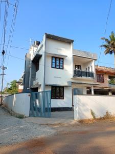 una casa blanca con una puerta delante de ella en Enna homestay, en Varkala