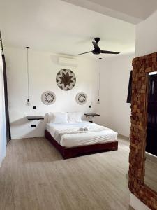 a white bedroom with a bed and a ceiling fan at The Confidential Mandalika in Kuta Lombok