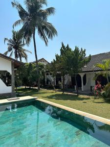 una piscina frente a una casa con palmeras en The Confidential Mandalika en Kuta Lombok