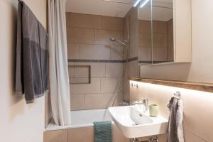 y baño con lavabo, bañera y ducha. en Fresh & Simple near Gstaad, en Gstaad