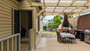 a patio with a table and chairs and a fireplace at Learmonth Guesthouse - Queenscliff in Queenscliff
