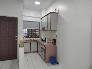 eine Küche mit einer braunen Tür und einem weißen Fliesenboden in der Unterkunft Luxpro Beachfront Homes Port Dickson in Port Dickson