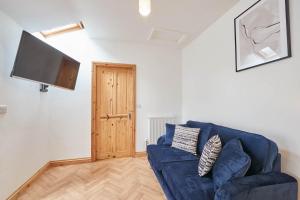a living room with a blue couch and a flat screen tv at Little Treasure in Whitby