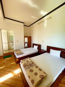 a bedroom with two beds and a mirror at MẠNH LÊ GIA HOTEL in Plei Brel (2)