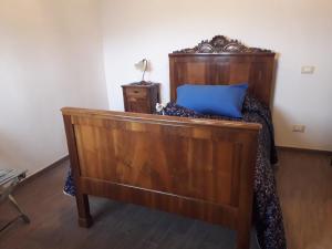 Una cama de madera con una almohada azul. en Á Ćà de Matilde en Ranzo-Borgo
