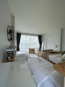 a white room with two beds and a tv at Phu Phop Kham in Ban Huai Khai