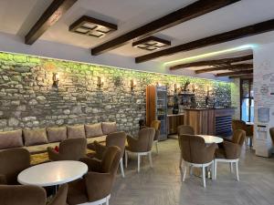 a restaurant with tables and chairs and a stone wall at Hannas Hostel in Berat