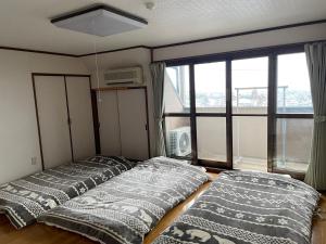 3 Betten in einem Zimmer mit Fenster in der Unterkunft Shinshulanson in Nagano