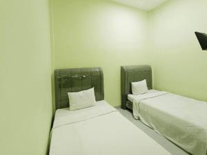2 letti in una camera con lenzuola e cuscini bianchi di Pudan Residence Balige By Helocus a Balige
