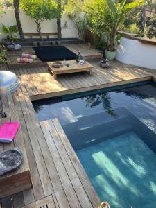 a swimming pool with a table and a wooden deck at Villa Java in Cassis