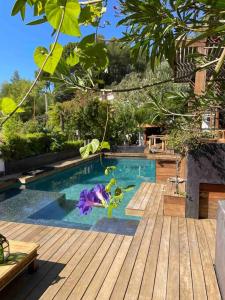 a swimming pool with a wooden deck and purple flowers at Villa Java in Cassis