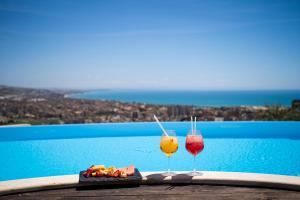 2 verres à vin assis sur une table à côté d'une piscine dans l'établissement Relais Villa Giuliana, à Licata