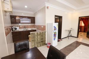 a kitchen with a refrigerator and a table in it at Taraf Al Asalah Villas in An Nimāş