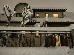 ein Haus mit einem schneebedeckten Zaun in der Unterkunft Shinshulanson in Nagano