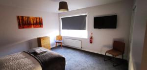 a bedroom with a bed and a window and a chair at Newtown Apartments in Boʼness