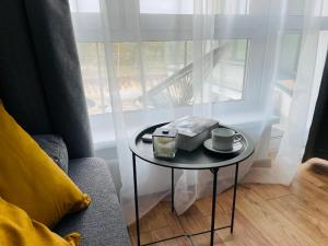 a small table with two cups on it next to a window at Apartament Foka - Rowy in Rowy