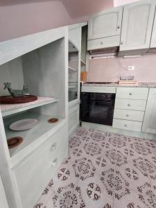 a kitchen with white cabinets and a tile floor at Da Zia Dorina in Siniscola
