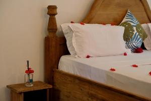 Bahati Villa في كيوينجوا: سرير عليه شراشف بيضاء و ورد احمر