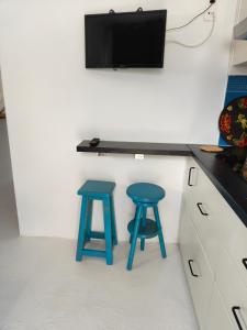 a kitchen with two blue stools and a tv on a wall at Loft la Caletilla in Caleta de Sebo