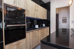 een keuken met houten kasten en een zwart apparaat bij Kallithea Comfort 3 Bd Balcony Family Apt in Athene