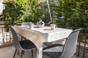 een witte tafel met stoelen en een parasol bij Kallithea Comfort 3 Bd Balcony Family Apt in Athene
