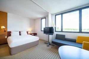 コケルにあるB&B HOTEL Calais Terminal Cité Europe 4 étoilesのベッドとテレビ付きのホテルルーム