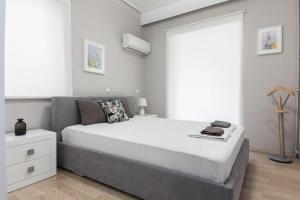 - une chambre avec un grand lit blanc et une fenêtre dans l'établissement Modern Luxury 2 Bedroom Apt in Agios Dimitrios, à Athènes