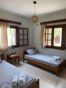 a bedroom with two beds and a couch and windows at Paradise house in Kriopigi