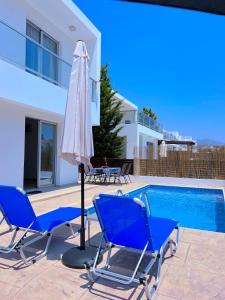 a patio with chairs and an umbrella next to a swimming pool at 3 Bedroom Coral Bay Beach Seaview Villa I Private Pool in Peyia