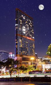 a tall building at night with the moon in the sky at WAIFIDEN Guangzhou Grand View Golden Palace Apartment - Free shuttle bus during the Canton Fair in Guangzhou
