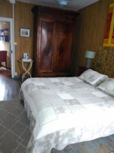 1 dormitorio con 1 cama grande y armario de madera en La Maison Bleue, en Brantôme