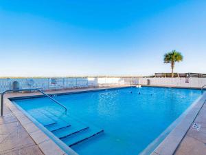 a large swimming pool with a palm tree in the background at Regency Towers 808 West in Pensacola Beach
